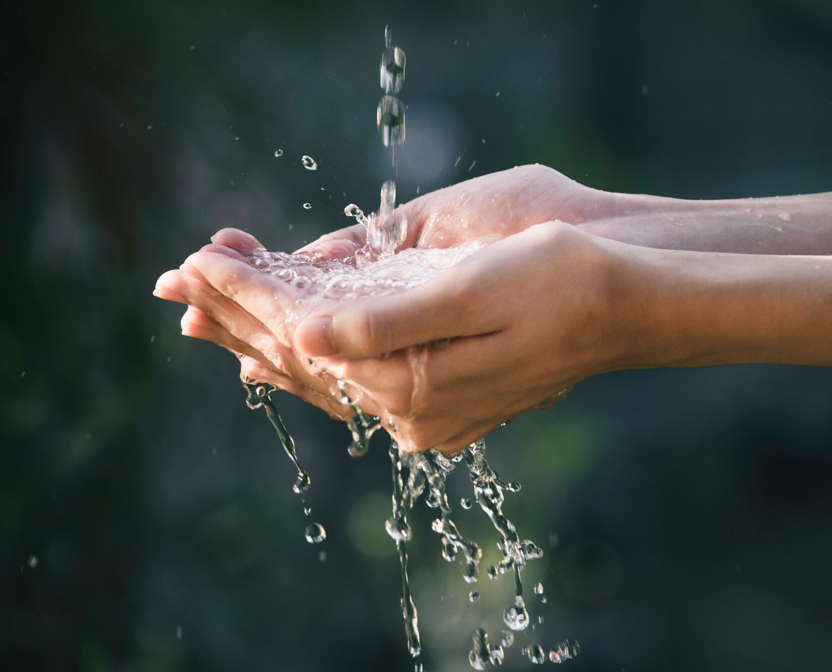 closeup water flow to hand of women for nature concept on the garden background.